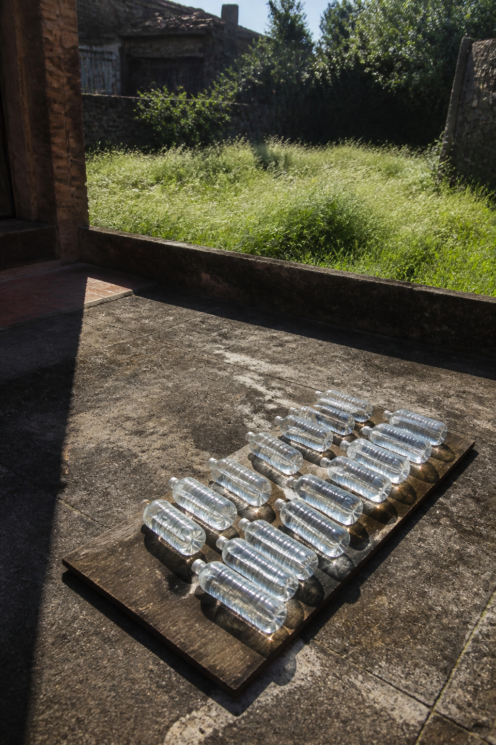 Flat bottles of water placed on a dark surface in sunlight.
