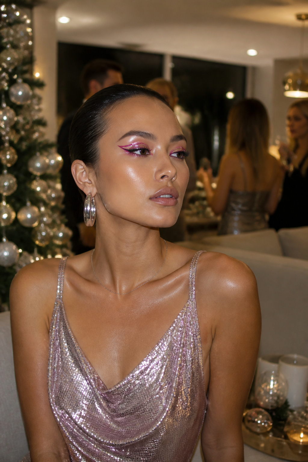 Model showcasing bold pink chrome eye makeup at a holiday gathering.