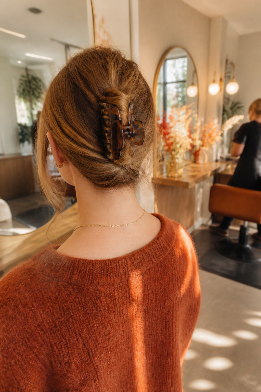 15 Cute Fall Hairstyles and Styles for 2026 2 Woman modeling a claw clip updo in a chic salon setting.