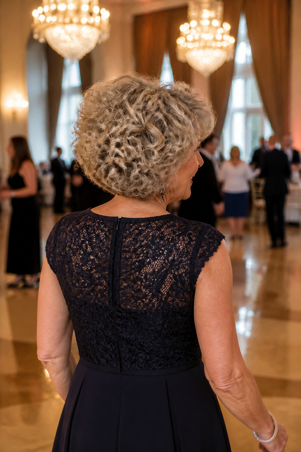 20 Medium Hairstyles for Women Over 60 (2026 Guide) 17 A woman with voluminous curls in an elegant ballroom.