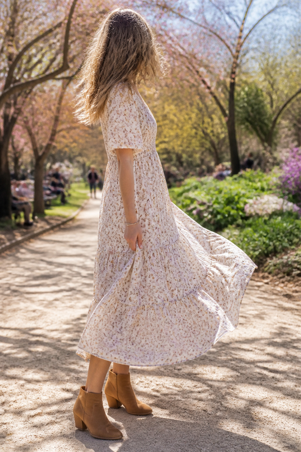 34 Spring Outfits to Copy for Warmer Weather in 2026 16 Model in a floral dress standing in a sunlit park.