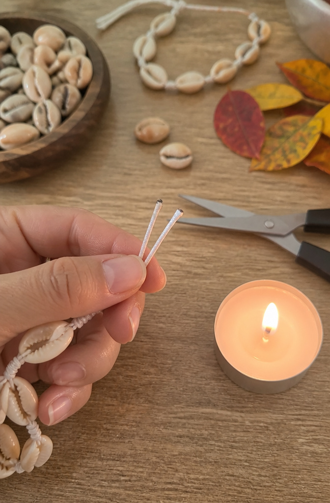 Shell Bracelet DIY: String, Drill or Glue Shells in 6 Steps 5 Melted cord ends of a bracelet with crafting tools nearby.